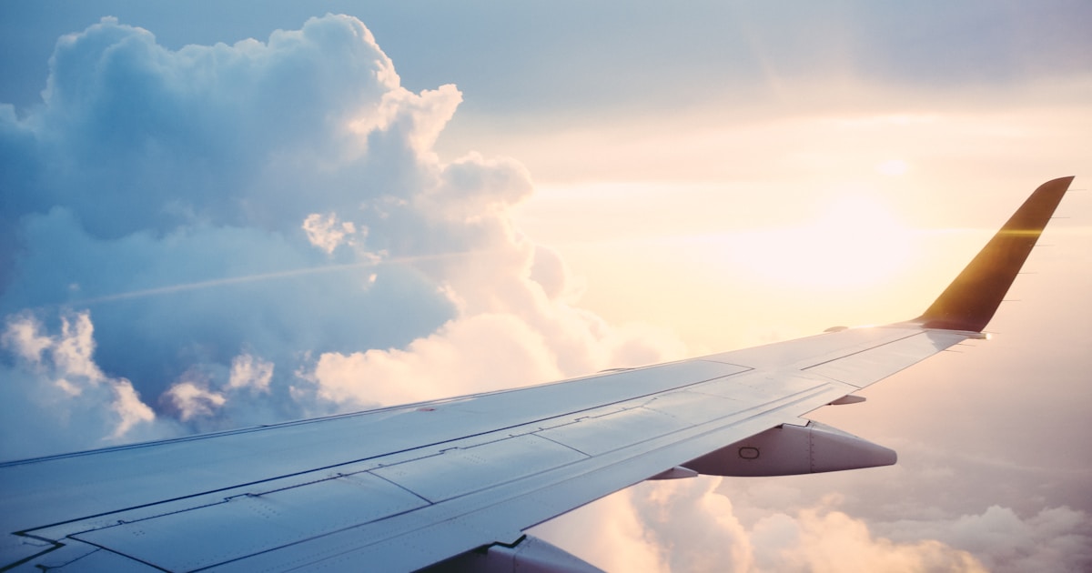 Avión aterrizando al atardecer con el aeropuerto internacional iluminado al fondo