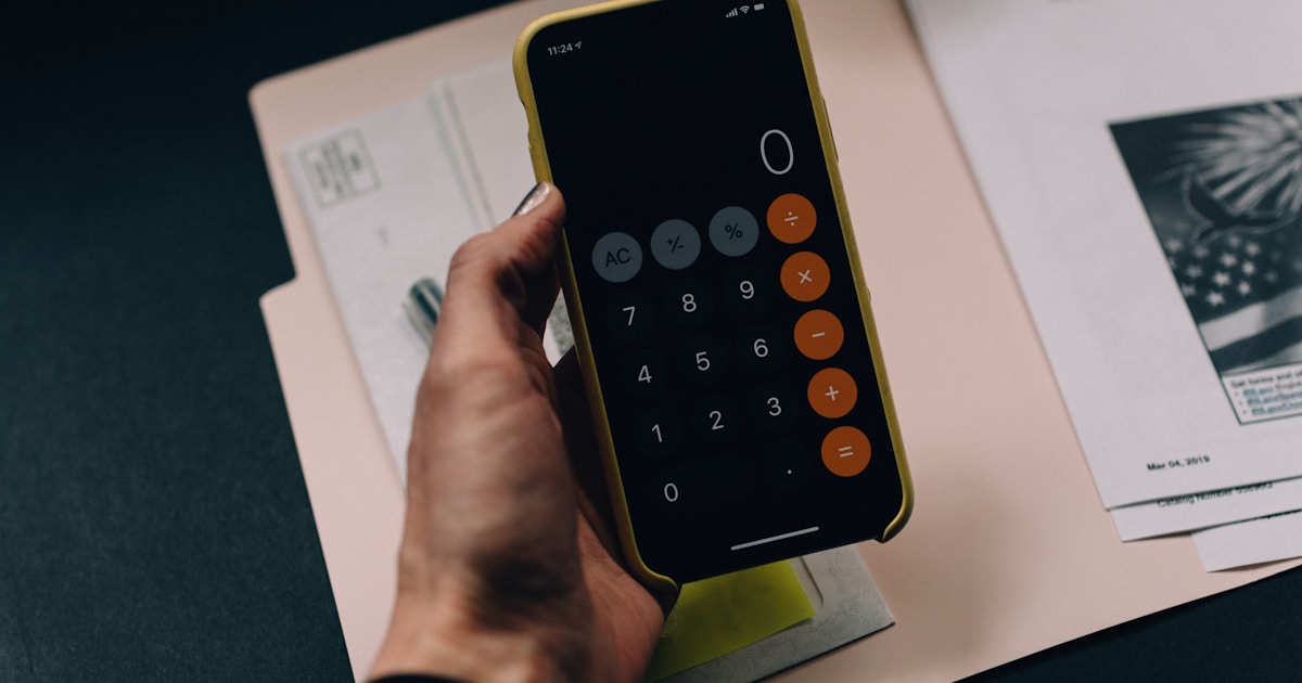 Calculadora y documentos sobre una mesa, representando cálculos de alquiler